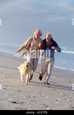 Ehepaar im Ruhestand am Strand mit ihrem Labrador Hund ausgeführt. Stockfoto