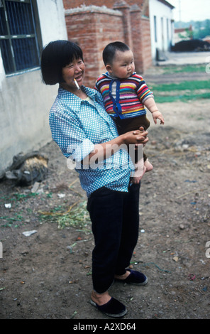 China 90er Jahre Provinz Anhui Mutter hält ein kleines Kind, das ein Zigarettendorf raucht Liufu Dorf 1998 HOMER SYKES Stockfoto