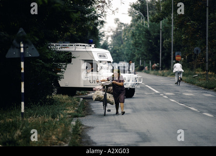Vukovar, Kroatien, unter serbischer Kontrolle, Februar 1992: eine Frau tragen ihre Versorgung mit dem Fahrrad nach Hause, wie ein UN-Fahrzeug verjagt. Stockfoto
