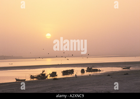Die Sonne geht über einen Blick auf Boote angedockt am Fluss-Ufer. Stockfoto
