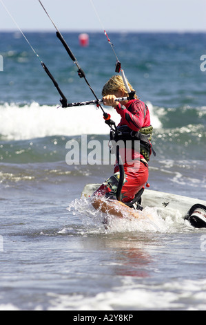 junge männliche Kitesurfer in rot nimmt seine Board und Kite durch die Wellen Weg von El Medano Strand Teneriffa-Kanarische Inseln-Spanien Stockfoto