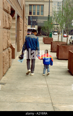 Afroamerikanischen Vater und Sohn im Alter von 28 und 4 Hand in Hand gehen Innenstadt. Chicago Illinois USA Stockfoto