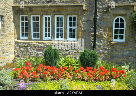 Stein-Ferienhaus in Lancashire Dorf Downham Ortschaft, UK, zeigt Windows steinernen Pfosten und einem Garten von roten Geranien Stockfoto