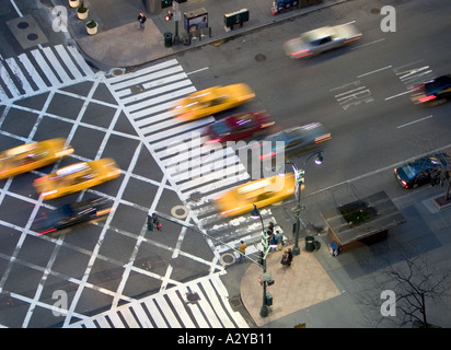 Verschwommene Taxis zu bewegen, über eine Kreuzung der East 42nd Street in New York City USA in der Abenddämmerung Stockfoto