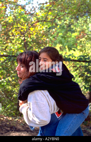 Tochter reiten auf Mütter zurück in die Stadt zu Fuß Alter 32 und 12. Austausch Wohltätigkeitsorganisationen Youth Festival Minneapolis Minnesota USA Stockfoto