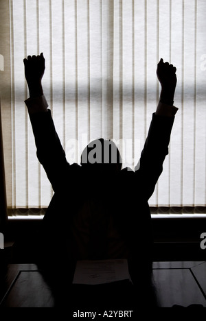 Silhouette eines Geschäftsmannes, hob seine Hände in seinem Büro Stockfoto