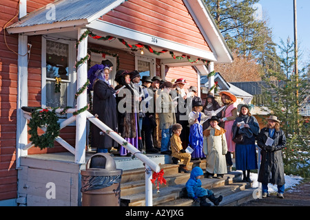 Bild einer Gruppe alter Menschen gemischt stehend auf der Treppe eine Oldtime westlichen Buidling singen Weihnachtslieder von Gesangbüchern. Stockfoto