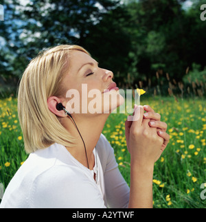 Frau im Kopfhörer Gänseblümchen riechen Stockfoto