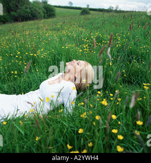 Blonde Frau, die im Feld liegen Stockfoto