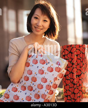 eine junge Chinesin Einkaufstaschen halten und Lächeln Stockfoto