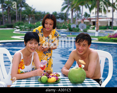 Chinesische junges Paar sitzt neben einem Schwimmbad Stockfoto