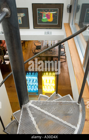 Ansicht von oben der Wendeltreppe nach unten in den offenen Wohnbereich mit Neon-Licht-Installation im Penthouse-Wohnung Stockfoto