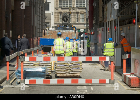 Straßensperren und Bauarbeiter in Schutzhüten und hohen Vis Weste geschlossen enge Straße Job Entladen Baustellenmaterial City of London England Großbritannien Stockfoto