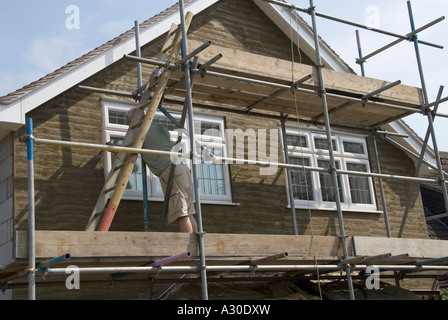 Gipser Arbeiten auf Gerüsten, die ersten Kratzer Mantel Sand und Zement rendern auf Block Wand Giebel das Ende der neuen Einfamilienhaus Essex England Großbritannien Stockfoto