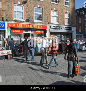 Shopper in Wentworth Street Teil der Petticoat Lane Market mit Kleidung schienen im Freien auf bürgersteig vor Retail Business Shop front London UK Stockfoto