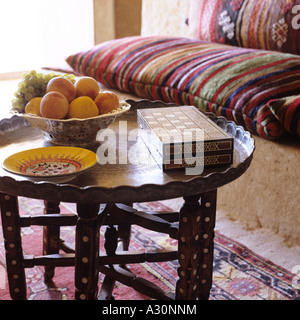 Marokkanischen Tisch mit Früchten und Schachbrett Intarsien und Sitzbänken gestreift Stockfoto