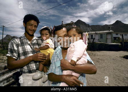 Mikrokosmos der Apartheid Kleinmond Südafrika 2 Männer mit 2 Babys auf Arm in einer lokalen Umgebung Stockfoto