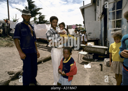 Mikrokosmos der Apartheid Kleinmond Südafrika 2 Männer mit einem Baby Kleinkinder vor einer Hütte mit Kleidung trocknen auf der Wäscheleine in einer schwarzen Nachbarschaft 1988 Stockfoto