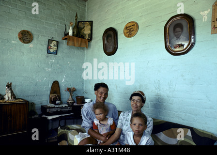 Mikrokosmos der Apartheid Kleinmond Südafrika 2 Frauen mit 2 Kleinkindern sitzen auf einem Sofa im Wohnzimmer mit Bildern an grünen Wänden 1988 Stockfoto