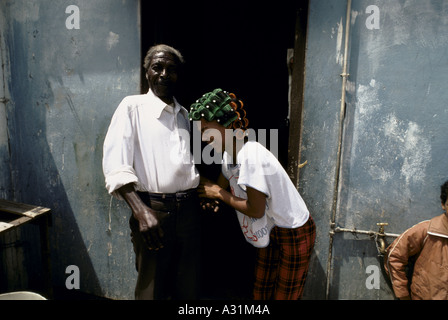 Mikrokosmos der Apartheid Kleinmond Südafrika einem lachenden schwarzen Frau mit Lockenwickler eine alte schwarze Mann durch eine Tür 1988 Stockfoto