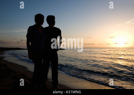 Junges Paar umarmt am Strand bei Sonnenuntergang Stockfoto