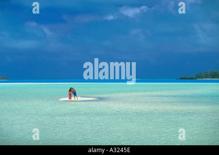 Paar küssen, während er auf eine kleine Sandbank mitten im klaren blauen Wasser auf den Cook Inseln Stockfoto