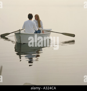 Ein junges Paar sitzt in einem Ruderboot langsam entlang des Wassers Stockfoto