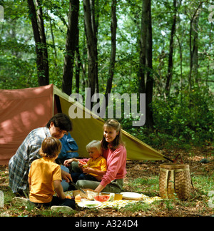 Vater Mutter und zwei Kinder mit einem Picknick auf den Campingplatz vor ihrem Zelt Stockfoto