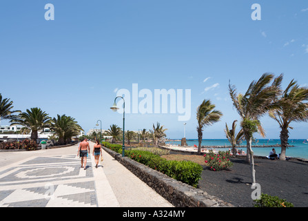 Paar zu Fuß entlang der Promenade am Strand von Playa de Las Cucharas, Costa Teguise, Lanzarote, Kanarische Inseln, Spanien Stockfoto