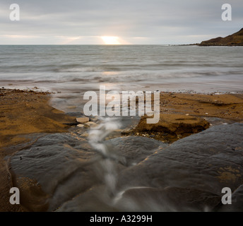 Ein Stream läuft ins Meer bei Sonnenuntergang auf Chapman s Pool Purbeck Dorset UK Stockfoto