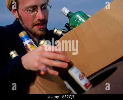 Person in den Zwanzigern recycling Bierflaschen Recycling Einheit North Wales UK Stockfoto