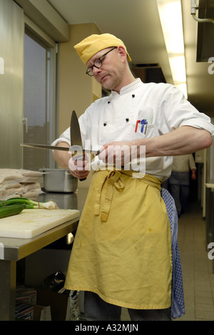 Der Koch und Küchenchef Stefan Voege in der Großküche, wenn sein Messer schärfen Stockfoto