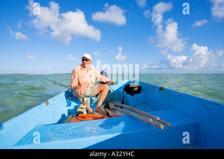 Bahamas, Abaco.  Mann fahren kleines Fischerboot mit Fliege Angelrute in der hand.  Modell veröffentlichte Foto. Stockfoto