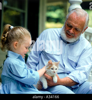 Ein Großvater hält eine Kätzchen während seiner Enkelin sanft das Kätzchen Haustiere Stockfoto