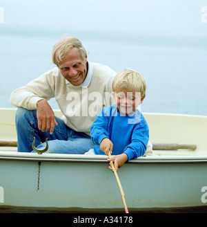 Ein Großvater blickt auf als seine Enkel Fische über die Seite des Bootes sind sie in Stockfoto