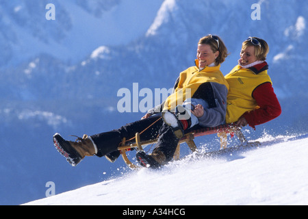 zwei Frauen auf einem Taboggan in den Bergen, Österreich, Alpen Stockfoto