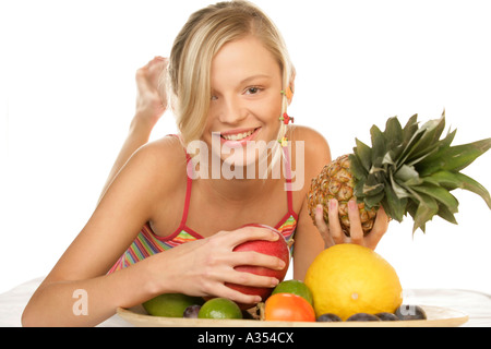 Junge Frau mit Früchten im Bett auf dem Bauch liegend Stockfoto