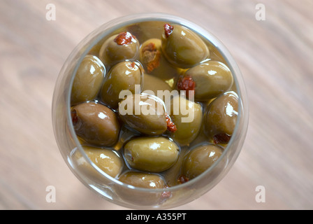 Grün gefüllte Oliven mit getrockneten Tomaten in einem Glas Sonnenblumenöl Stockfoto