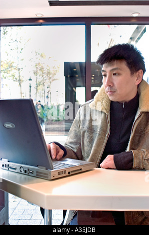 Chinesischer Mann im Mc-Donald Restaurant, Blick auf Laptop-Computer-Bildschirm am Tisch, paris McDonald's Restaurant, Tisch Stockfoto