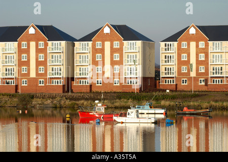 Moderne Mehrfamilienhäuser mit Blick auf Cardiff Bay Waterfront im frühen Morgenlicht mit festgemachten Boote Stockfoto