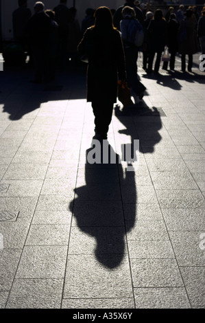 lange Winter Sonne Schatten der Frau zu Fuß auf Fußweg mit einer Handtasche in dublin Stockfoto
