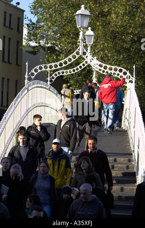 Menschen, die über die Hapenny ha Penny Brücke über den Fluss Liffey in Dublin auf eine arbeitsreiche Zeit vertikale Stockfoto