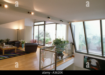 Modernes Wohnzimmer in Stadt Dachgeschossausbau mit poliertem Holzfußboden und großen Fenstern mit Blick auf Terrasse, Dachgarten Stockfoto