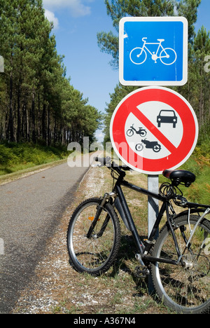 Fahrrad geparkt gegen ein Verkehrszeichen auf einen Radweg durch den Wald der Landes Frankreich Stockfoto