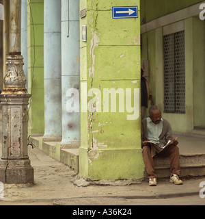 Mann sitzt auf einem Schritt Lesen einer Zeitung Havanna Kuba Stockfoto
