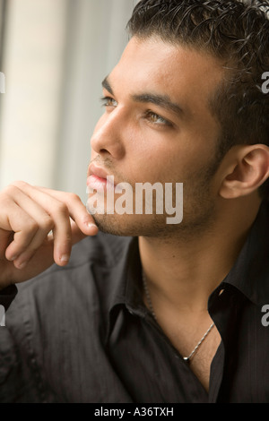 Durchdachte und attraktive junger Mann schaut aus dem Fenster Stockfoto