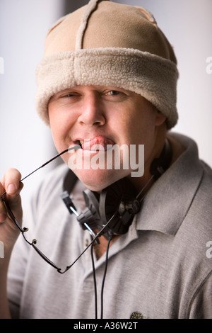 Comic-Porträt eines jungen Mannes in eine Pelzmütze, seine Zunge mit Kopfhörer um den Hals Stockfoto