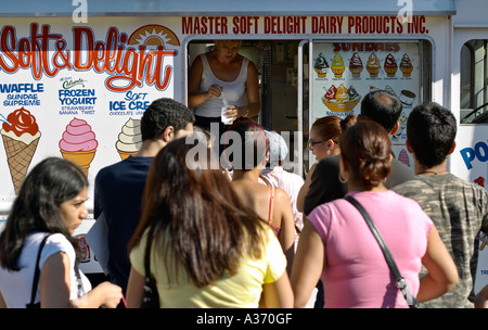 Menschen in der Schlange zu Eis an einem heißen Sommertag zu kaufen. Schwerpunkt liegt auf den Eiswagen und der Verkäuferin. Stockfoto