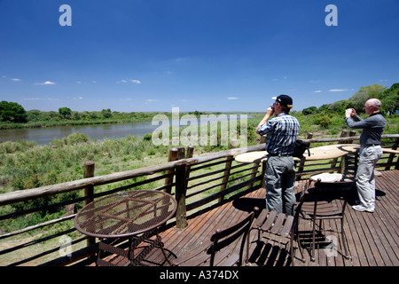 Touristen auf der Aussichtsplattform des unteren Sabie Camp mit Blick auf den Sabie River in Südafrikas Krüger Nationalpark. Stockfoto