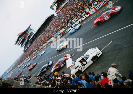 1967 startete das 24-Stunden-Rennen in Le Mans mit dem Ford GT40, der von Dan Gurney und A.J. Foot oben rechts gefahren wurde, während Mike Spence im Chaparral 2F immer noch seinen Sicherheitsgurt anschnallt. Stockfoto